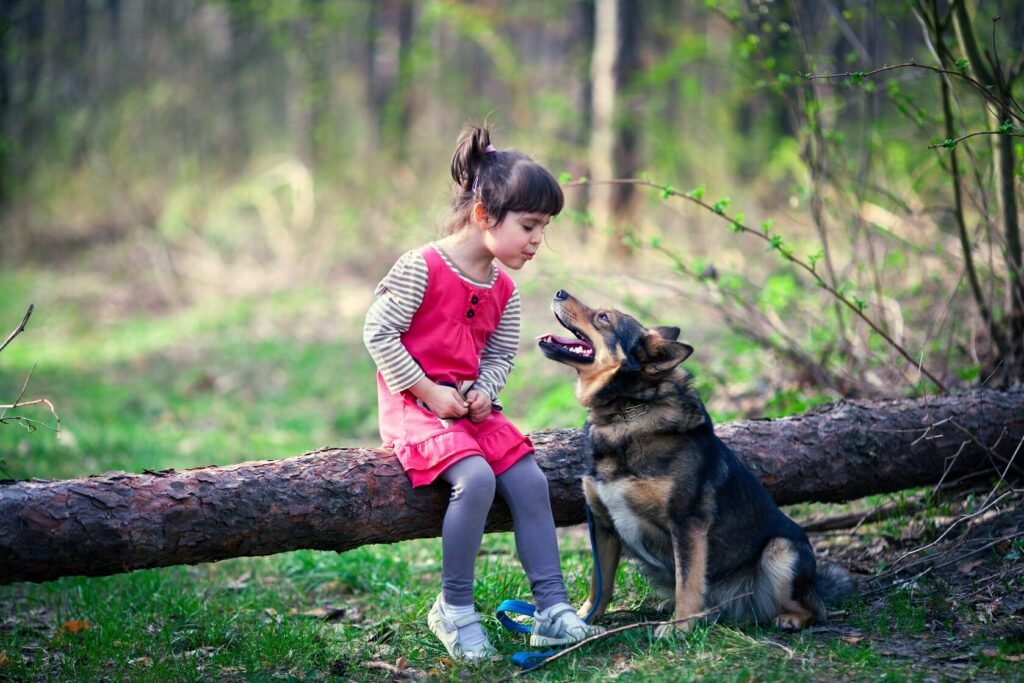 Petite fille assise sur un tronc qui parle avec son chien