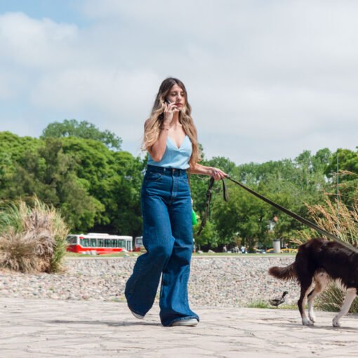 Femme en balade avec son chien en laisse, distrait par son téléphone portable, illustrant l'impact des écrans sur la relation humain-chien et l'éducation canine bienveillante.